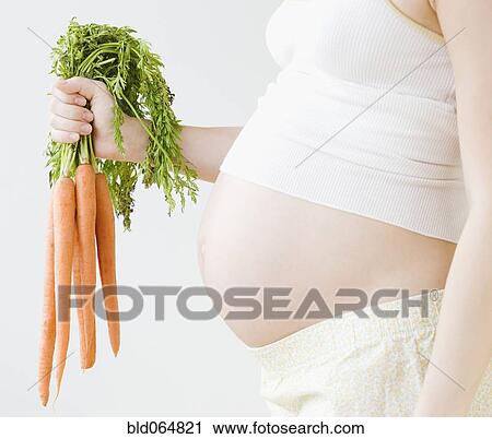 Pregnant Asian woman holding bunch of carrots View Large Photo Image Stock Image - Pregnant Asian woman holding bunch of carrots. Fotosearch
