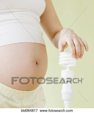 Stock Photo - Pregnant Asian woman holding cfl lightbulb. Fotosearch