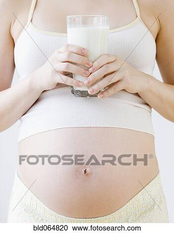 Stock Image - Pregnant Asian woman holding glass of milk. Fotosearch