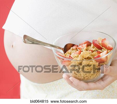 Stock Photography - Pregnant Asian woman holding healthy cereal. Fotosearch