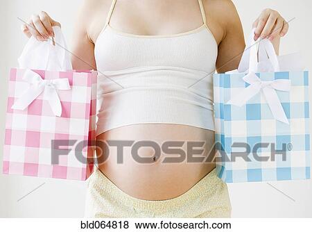 Stock Photo - Pregnant Asian woman holding pink and blue shopping bags. Fotosearch