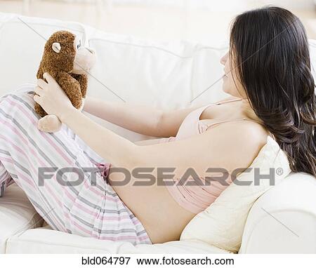 Stock Photo - Pregnant Asian woman holding stuffed animal. Fotosearch
