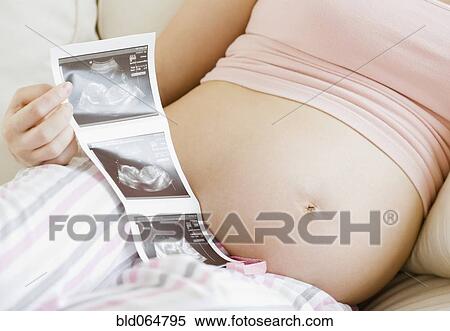 Stock Photography - Pregnant Asian woman looking at ultra sound pictures. Fotosearch