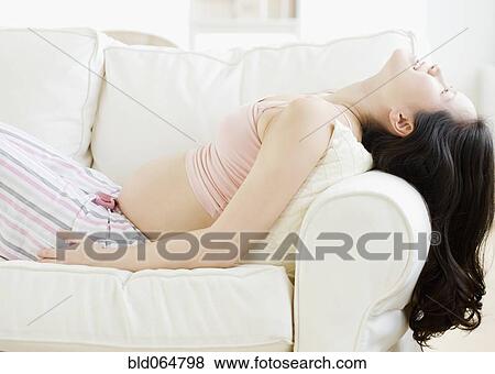 Pregnant Asian woman reclining on sofa View Large Photo Image Stock Photo - Pregnant Asian woman reclining on sofa. Fotosearch