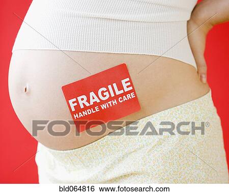 Stock Photograph - Pregnant Asian woman with fragile sticker on stomach. Fotosearch