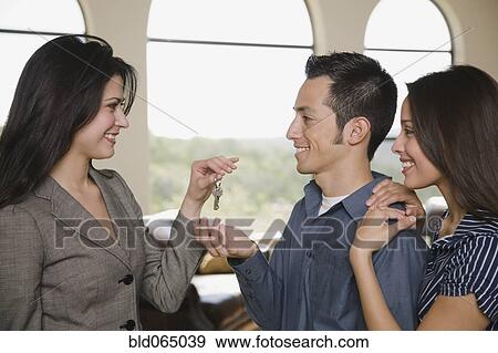 Realtor handing couple keys new home View Large Photo Image Stock Photo - Realtor handing couple keys new home. Fotosearch