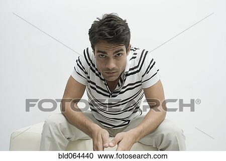 Stock Image - Serious Hispanic man sitting. Fotosearch