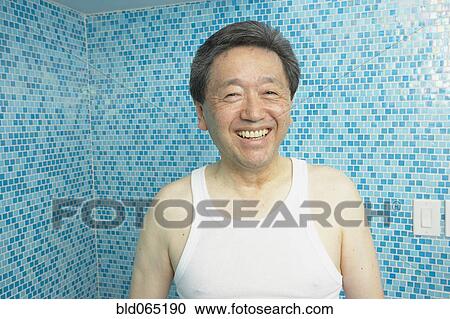 Stock Image - Smiling Asian man in bathroom. Fotosearch