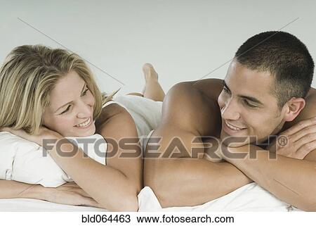 Stock Image - Smiling Hispanic couple laying in bed. Fotosearch