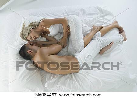 Stock Photo - Smiling Hispanic couple laying in bed. Fotosearch