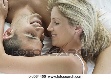 Stock Photography - Smiling Hispanic couple laying in bed. Fotosearch