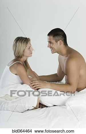 Picture - Smiling Hispanic couple sitting in bed. Fotosearch
