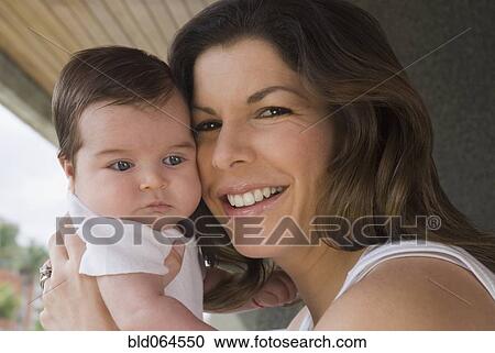 Stock Image - Smiling Hispanic woman holding baby. Fotosearch