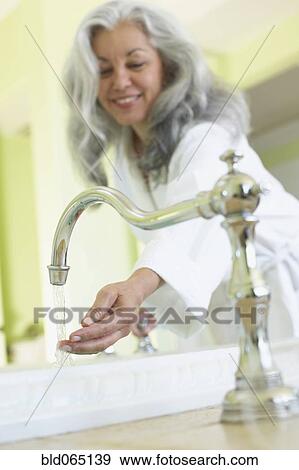 Stock Photo - Smiling woman checking water temperature in spa. Fotosearch