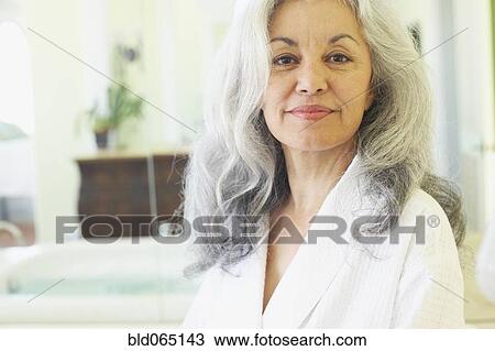 Stock Image - Smiling woman wearing bathrobe in spa. Fotosearch