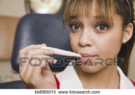 Stock Photography - Teenage girl taking temperature with thermometer. Fotosearch