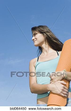Stock Image - Woman holding yoga mat. Fotosearch