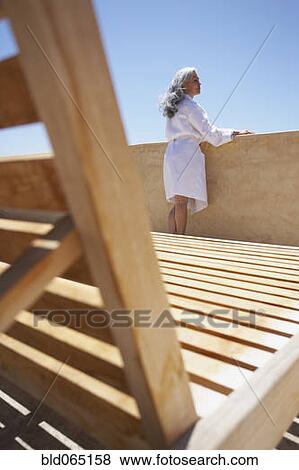 Stock Photo - Woman looking over balcony at resort. Fotosearch