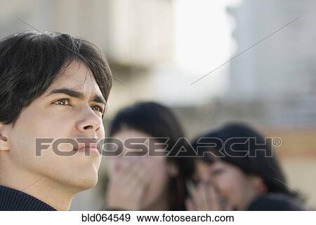 Stock Photo - Women laughing at Hispanic man. Fotosearch