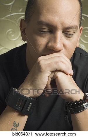 Stock Image - Worried Hispanic man with eyes closed. Fotosearch