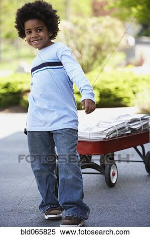 Stock Photography - African boy pulling wagon of newspapers for recycling . Fotosearch