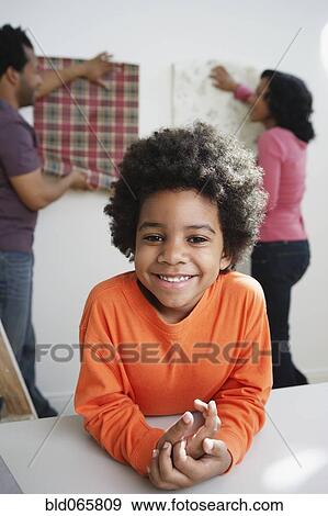 Stock Photo - African boy smiling while parents choose wallpaper. Fotosearch