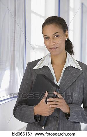 Stock Photo - African businesswoman holding binder. Fotosearch