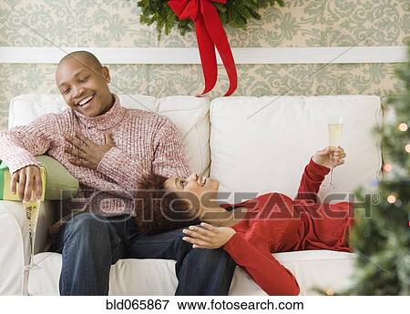 Stock Photo - African couple drinking Champagne at Christmastime. Fotosearch