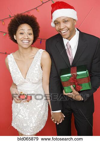 Stock Photo - African couple holding Christmas presents. Fotosearch