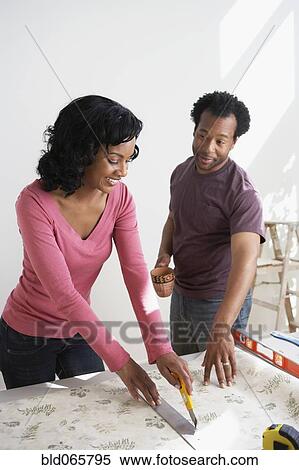 Stock Photography - African couple measuring wallpaper. Fotosearch