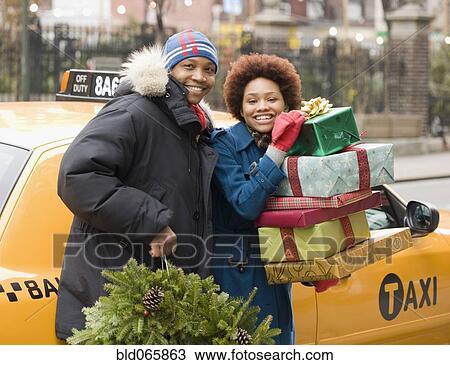 Stock Image - African couple with Christmas presents and wreath. Fotosearch