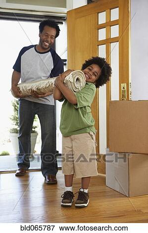 Stock Photo - African father and son carrying carpet into new home. Fotosearch