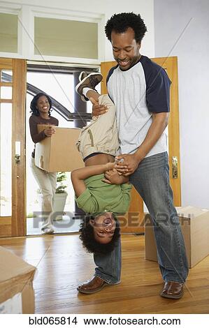 African father holding son upside down in new home View Large Photo Image Picture - African father holding son upside down in new home. Fotosearch
