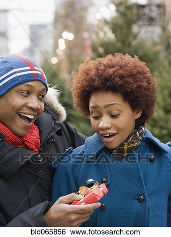 Stock Photograph - African man giving girlfriend Christmas present. Fotosearch