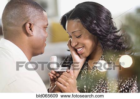 Stock Photo - African man giving girlfriend engagement ring. Fotosearch