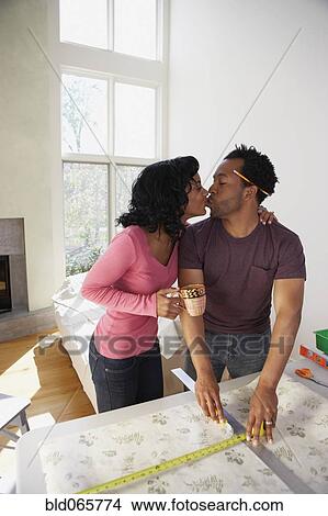 African man measuring wall paper getting kiss from wife View Large Photo Image Picture - African man measuring wall paper getting kiss from wife. Fotosearch