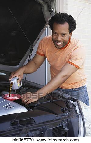 African man pouring oil into car engine View Large Photo Image Stock Image - African man pouring oil into car engine. Fotosearch