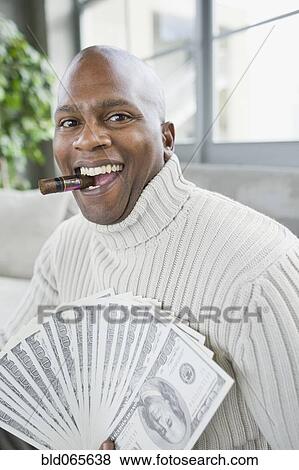 African man smoking cigar and holding 100 dollar bills View Large Photo Image Stock Photo - African man smoking cigar and holding 100 dollar bills. Fotosearch
