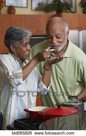 Stock Photograph - African man tasting wife’s cooking. Fotosearch