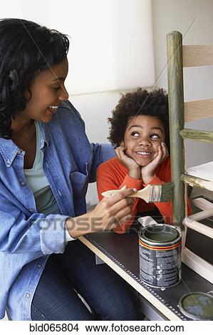 Picture - African mother and son painting rocking chair. Fotosearch
