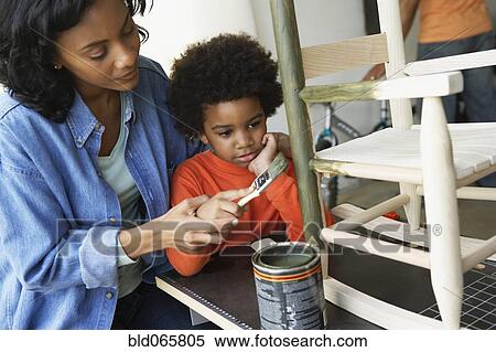 Stock Photography - African mother and son painting rocking chair. Fotosearch