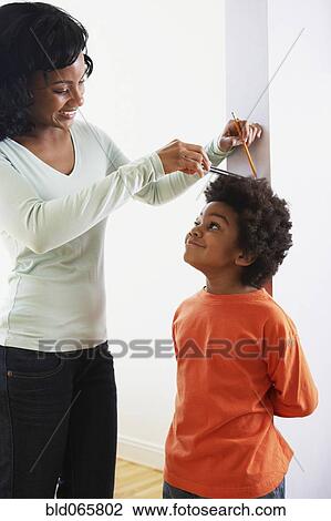 Stock Image - African mother measuring son’s height. Fotosearch