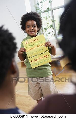Stock Image - African parents watch while son explains chores. Fotosearch