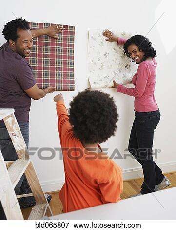 Stock Photo - African son helping parents choose wallpaper. Fotosearch