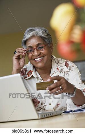 Stock Image - African woman ordering merchandise online with credit card. Fotosearch