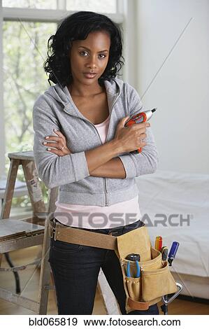 Stock Photo - African woman with drill and toolbelt. Fotosearch