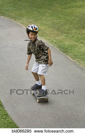 Stock Photography - Asian boy skateboarding downhill. Fotosearch