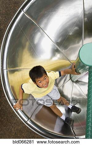 Asian boy sliding down circular slide View Large Photo Image Stock Image - Asian boy sliding down circular slide. Fotosearch