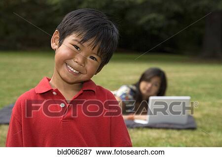 Asian boy smiling with mother in background View Large Photo Image Stock Photo - Asian boy smiling with mother in background. Fotosearch