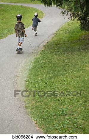 Picture - Asian boys skateboarding downhill. Fotosearch